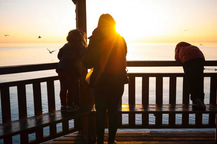 family looking over ocean at sunset - grant trevithick dallas real estate investor academy